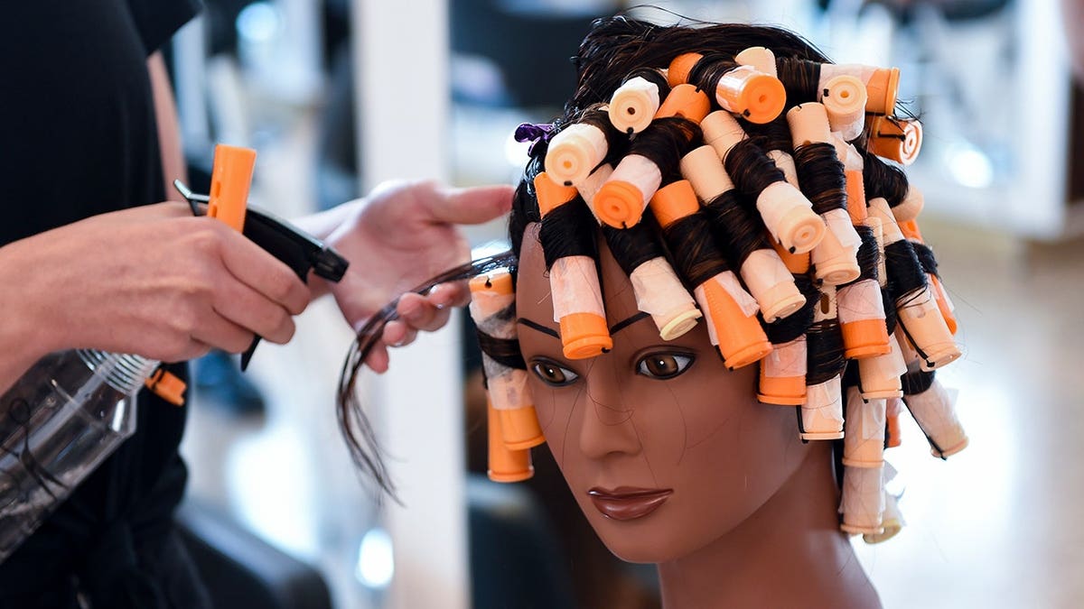 Student Alex Mancuso practices spiral perm technique on mannequin head.