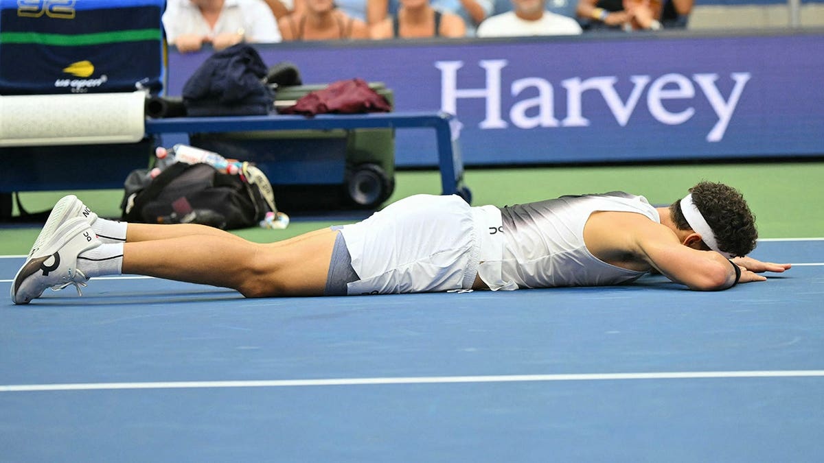 Ben Shelton lies on the court after falling during the US Open men's singles final.