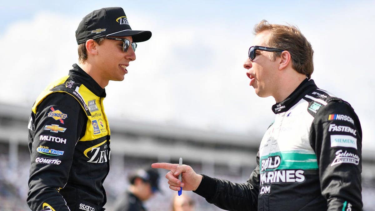 Brad Keselowski and Carson Hocevar talk on the grid during NASCAR practice.