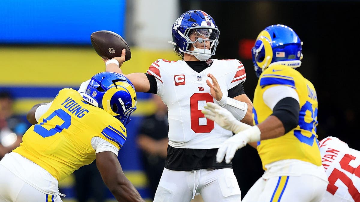 Byron Young of the Los Angeles Rams tackles Jaxson Dart of the New York Giants after a pass.