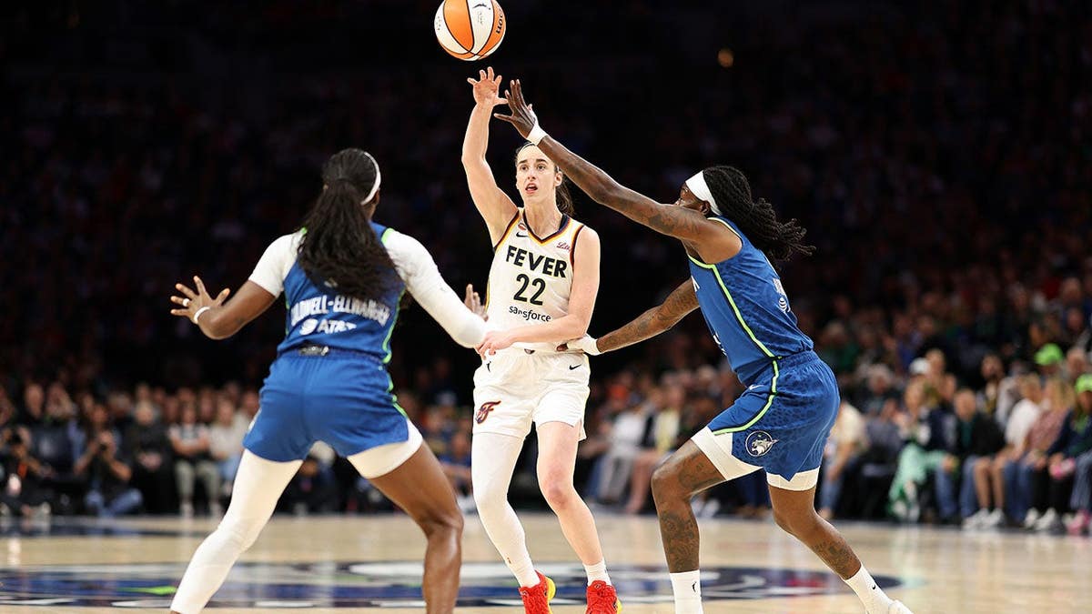 Caitlin Clark passes the ball against Maya Caldwell and Natasha Howard at Target Center.