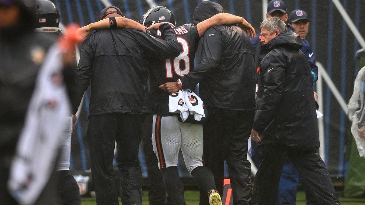 Caleb Williams is helped off the field at Soldier Field.