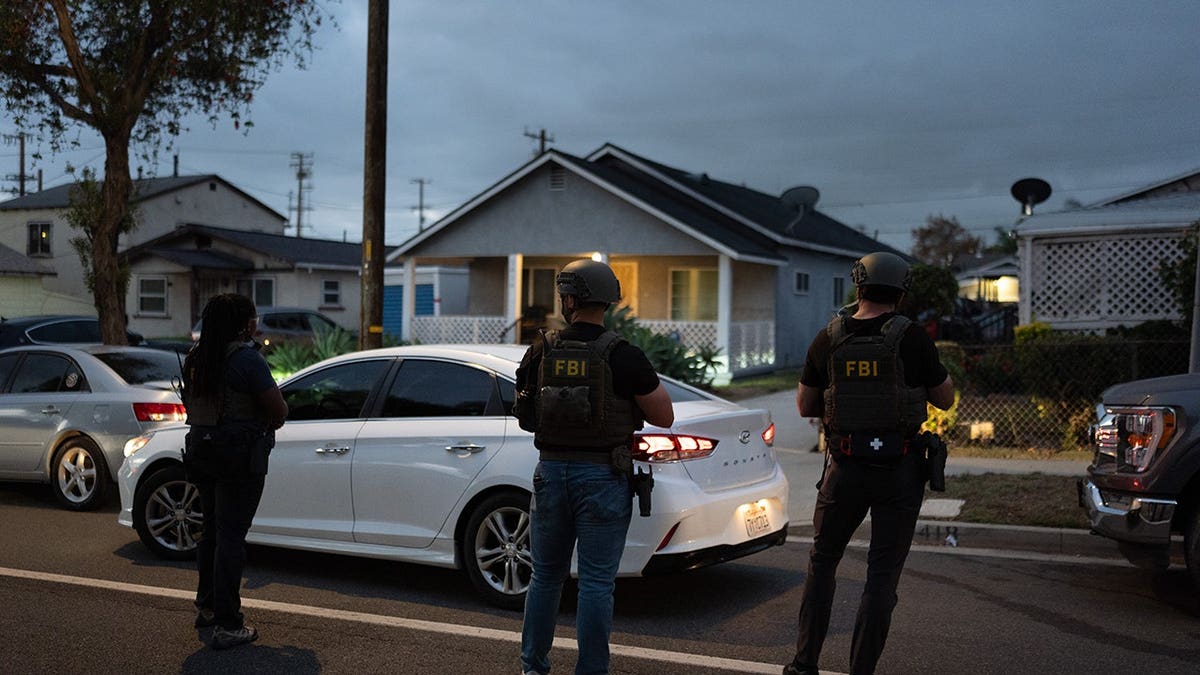 FBI agents stand outside a home in Los Angeles where Lakiya Malone is charged with fraud.