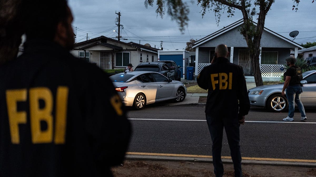 FBI agents stand outside a home in Los Angeles where Lakiya Malone is charged with fraud.