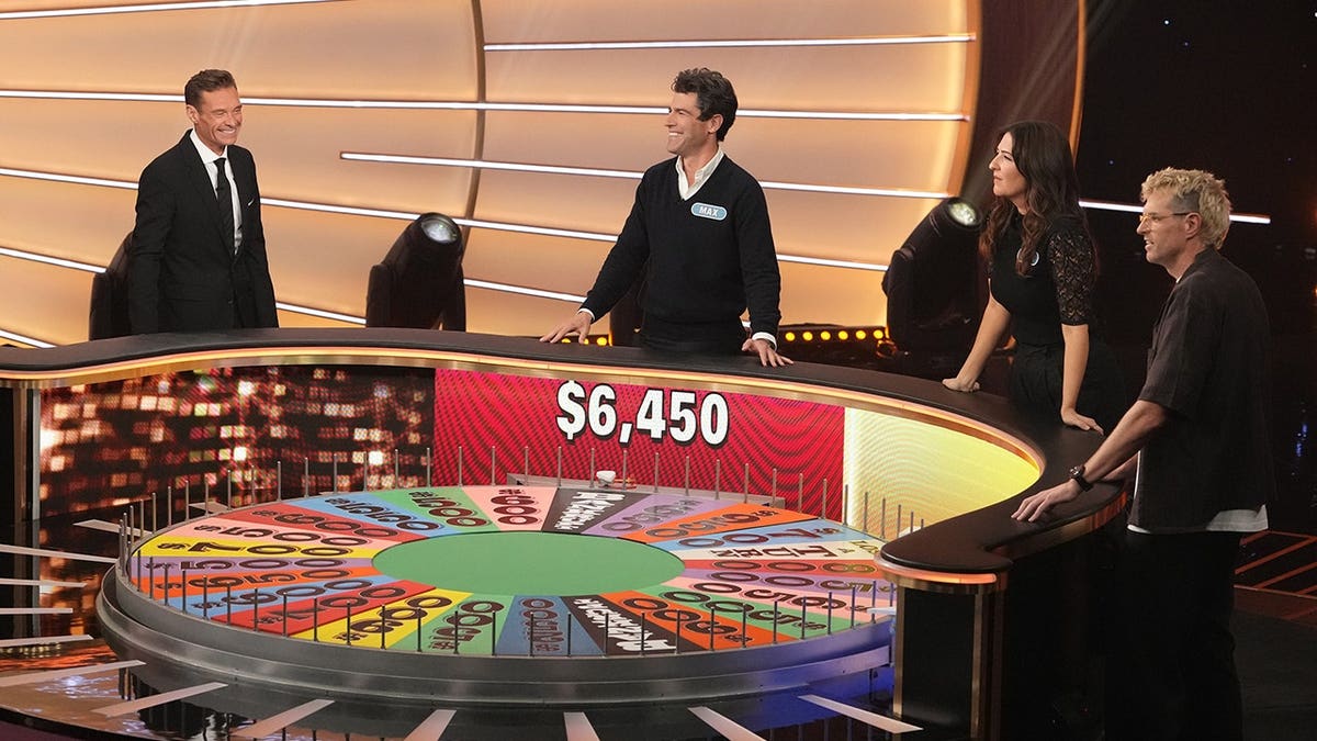 Ryan Seacrest stands with Max Greenfield, D'Arcy Carden and Timothy Simons near the Wheel of Fortune.