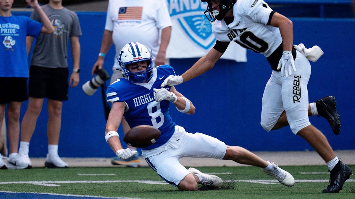 Chase Jacob drops a pass as Lucas Young defends during a football game.