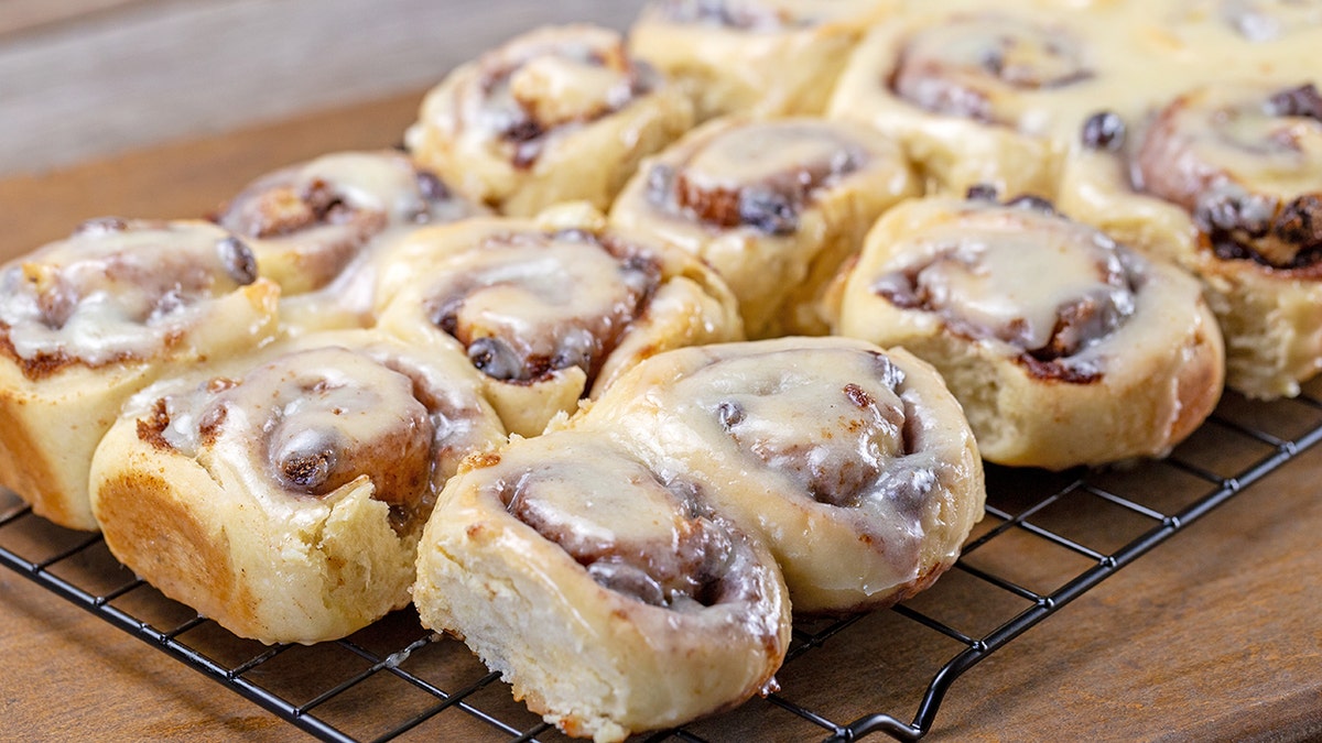 Homemade cinnamon rolls are shown on a cooling rack.