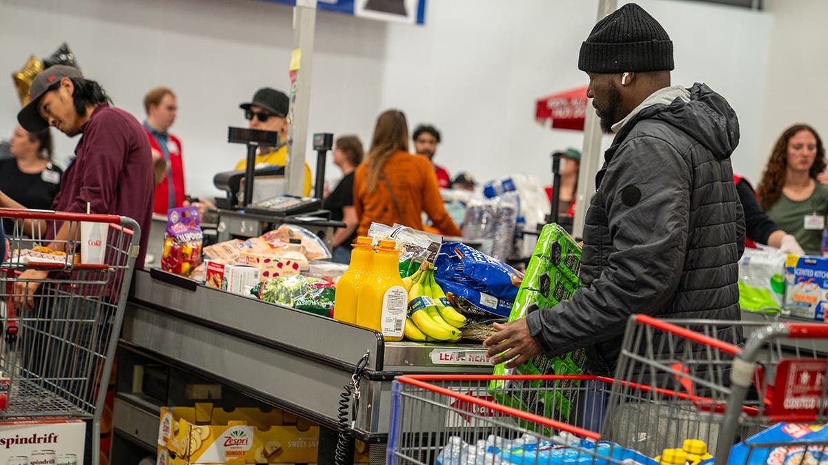 Shoppers unload groceries at a checkout counter inside a Costco Wholesale store.
