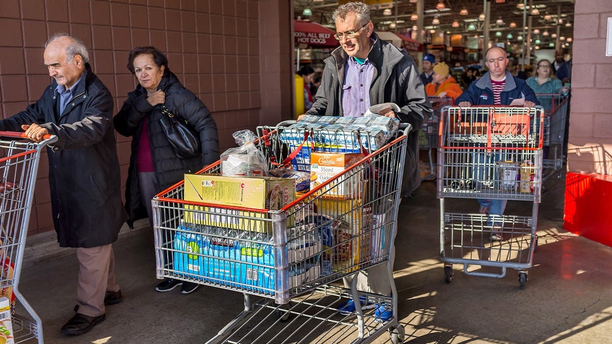 Costco shoppers push packed carts outside the store.