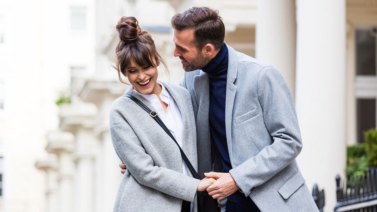 Couple flirts on a city street in London during autumn.