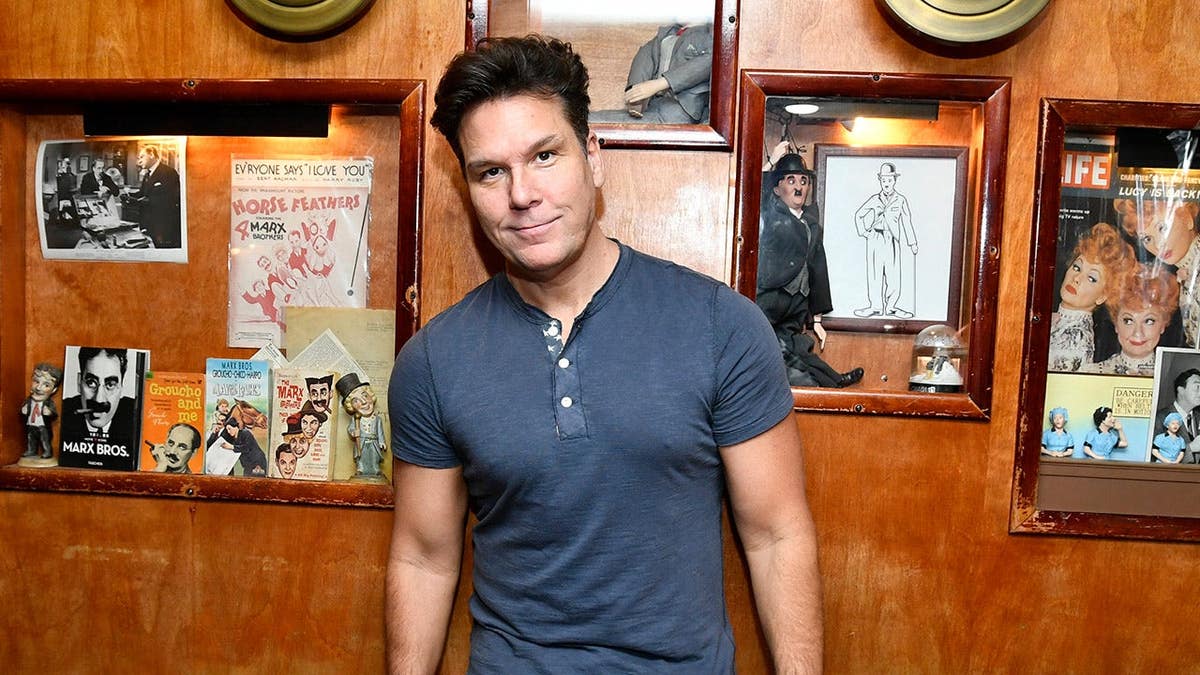 Dane Cook poses in blue shirt