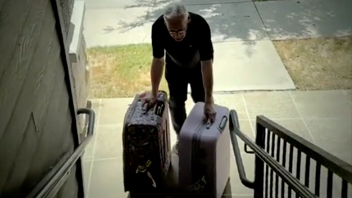 Donald Johnson carrying two suitcases up a flight of stairs.
