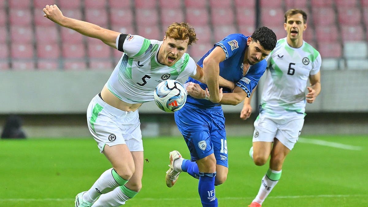 Dor Turgeman of Israel and Jake O'Brien of Ireland compete for the ball during a soccer match.