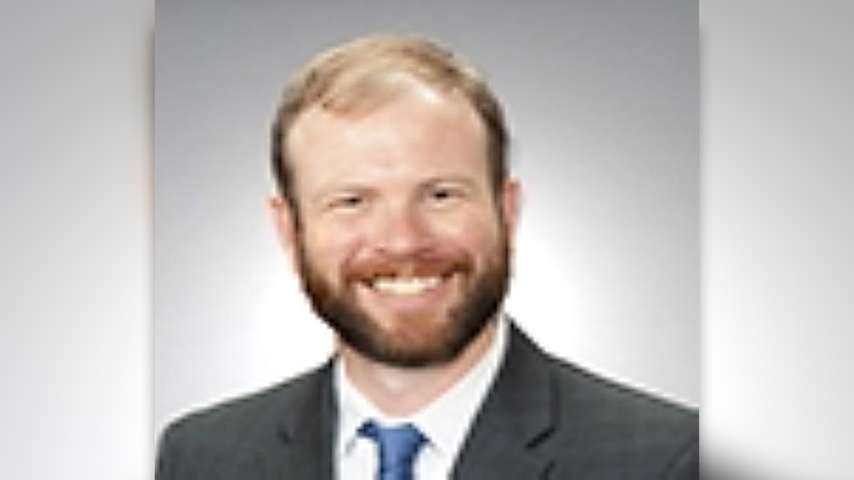 A blurry photo showing Dr. Evans in a suit and tie, he has thinning, light colored hair and a full beard