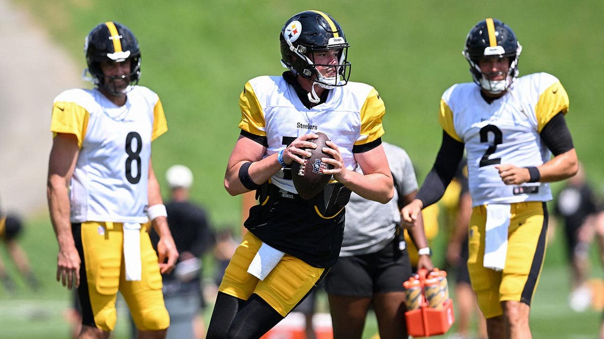 Drew Allar looks to pass during Steelers practice as Aaron Rodgers and Mason Rudolph watch.