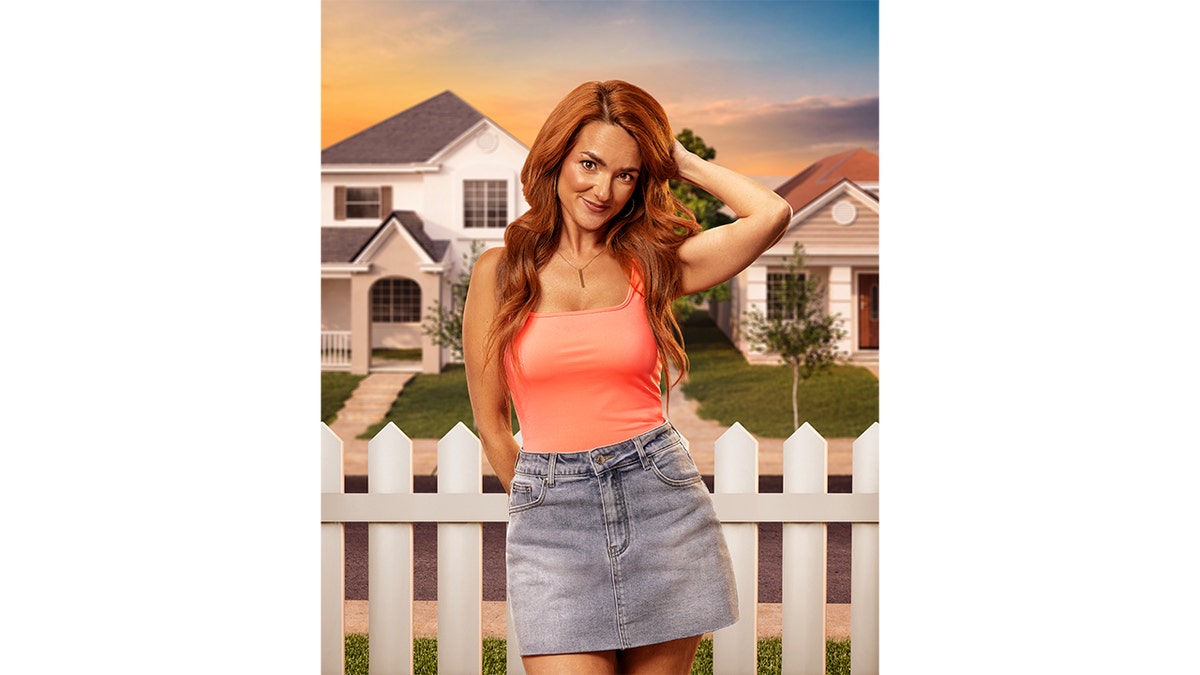 Emily Smith poses with one hand behind her head in front of suburban houses.