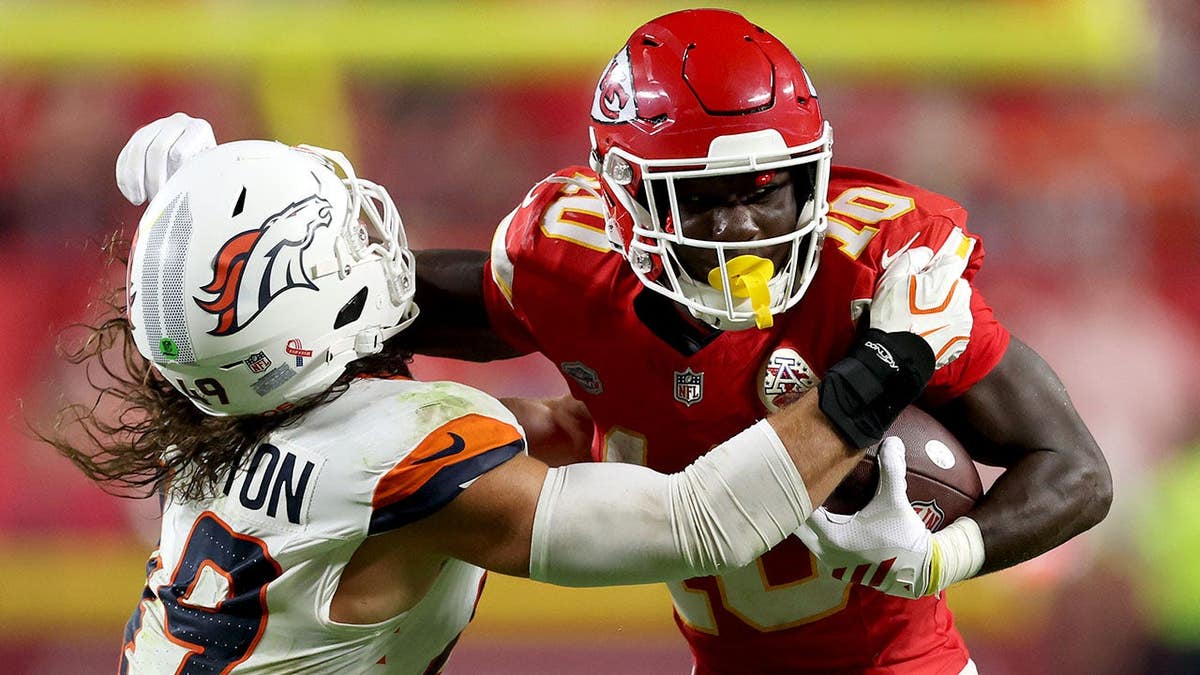 Emmett Johnson #10 runs with the ball against Alex Singleton #49 during an NFL game at Arrowhead Stadium.