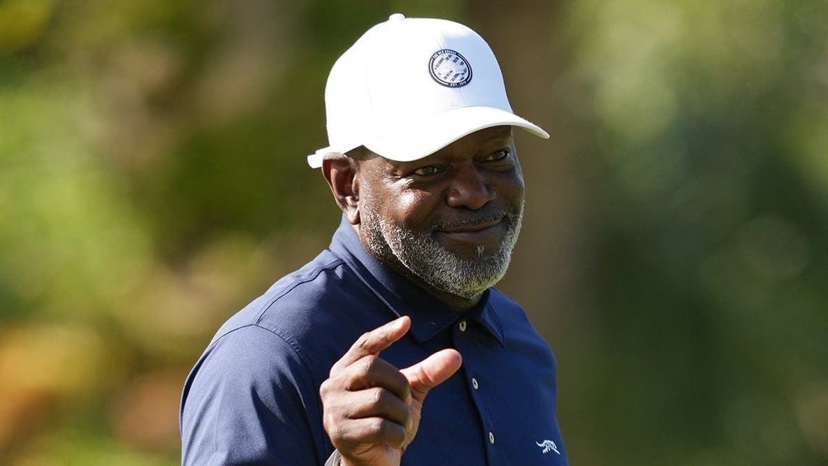 Emmitt Smith reacts after a shot on the 15th hole during a golf tournament.