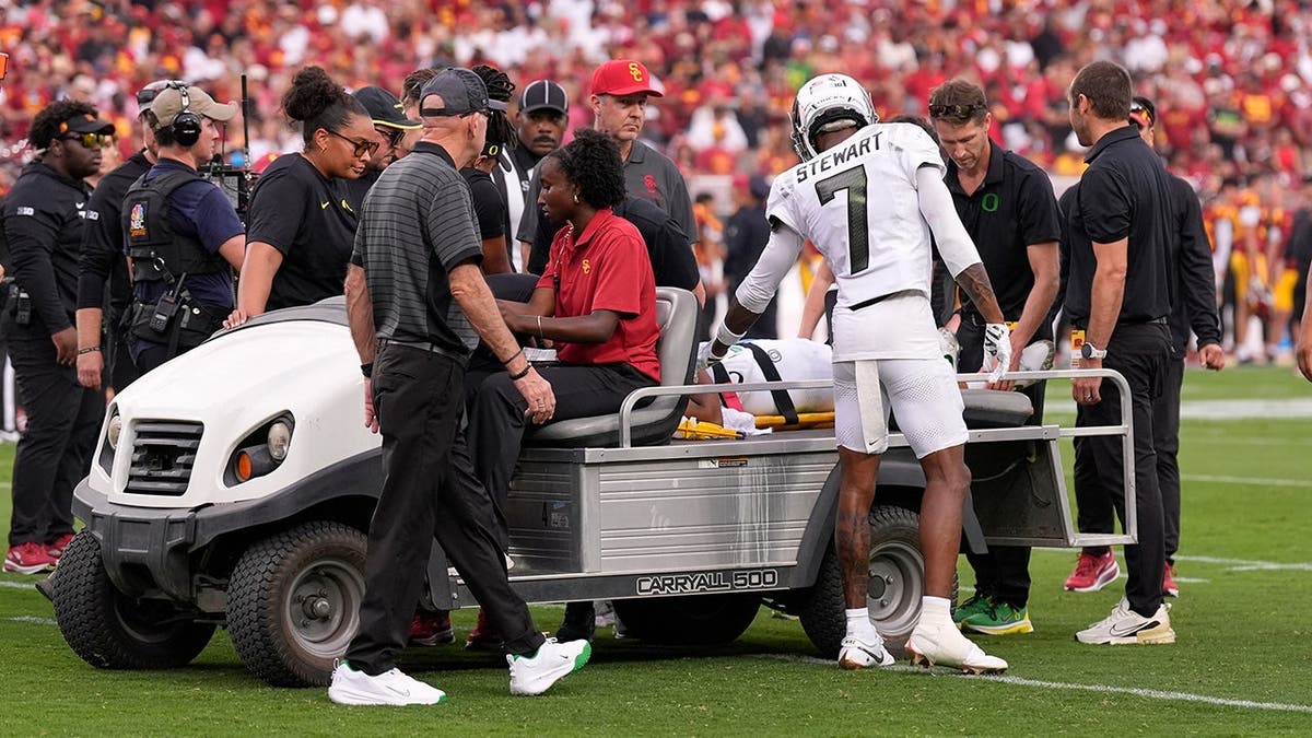 Evan Stewart looks on as Dante Moore is carted off the field following a tackle.
