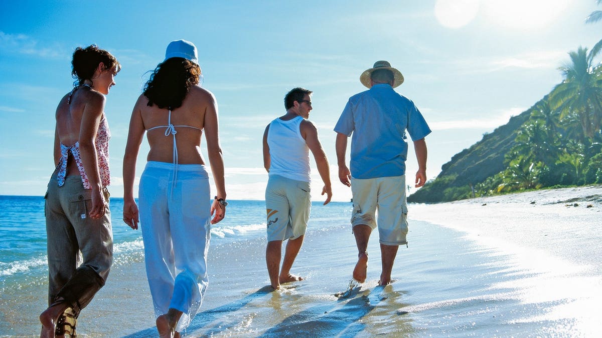 Two couples walk along a shore in Fiji.