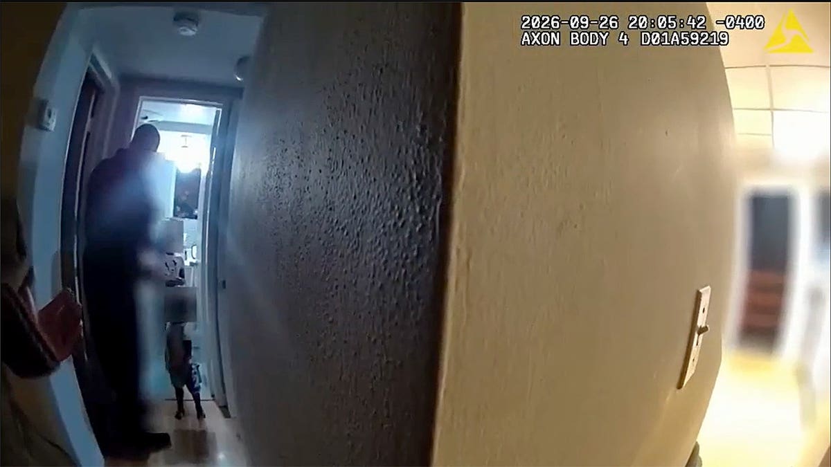 a blurred face of a 2-year-old boy standing in a doorway talking to police