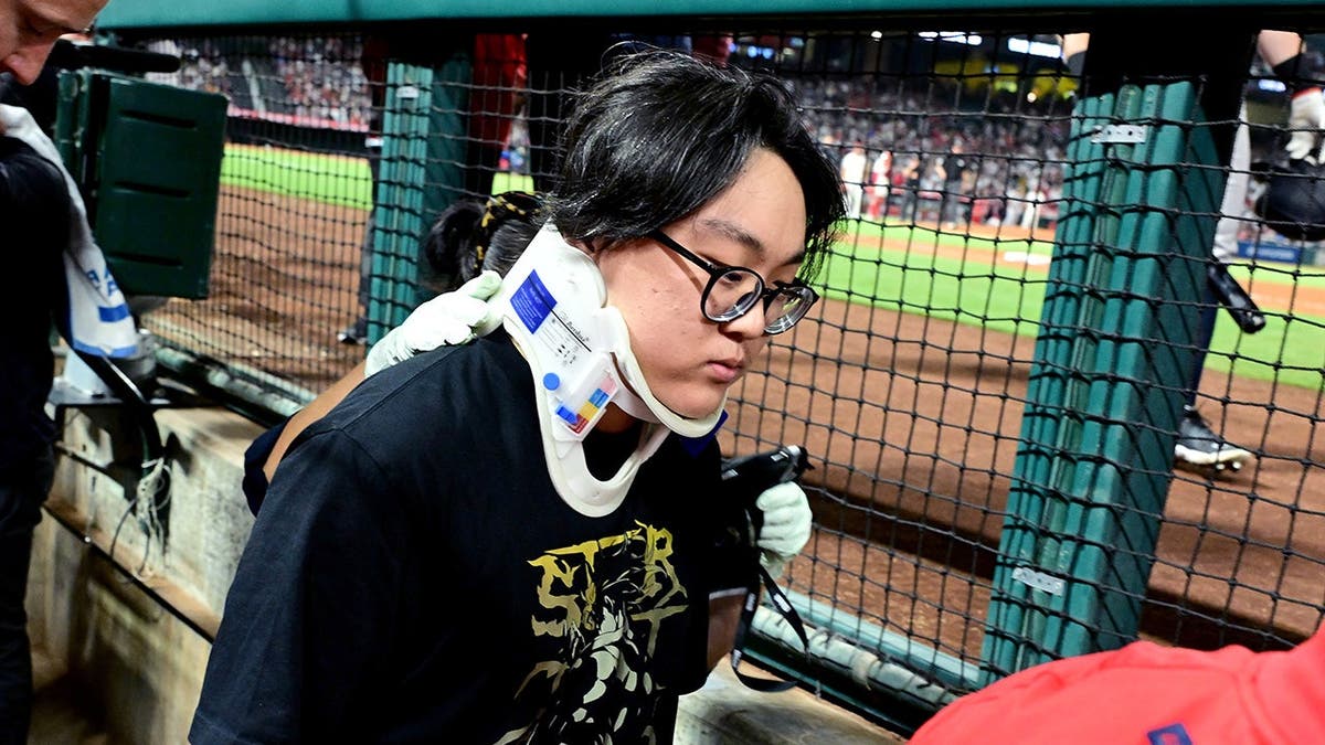 Medical personnel carry away a photographer after a foul ball hits his head during a baseball game.