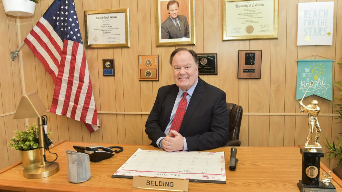 Dennis Haskins poses for a photo behind a desk