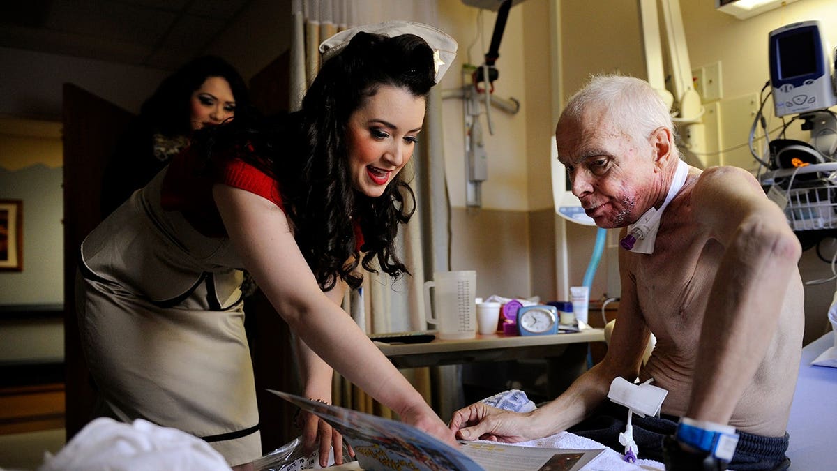 Gina Elise and James Oliver look over a Pin-Ups For Vets calendar at the Denver VA Medical Center.