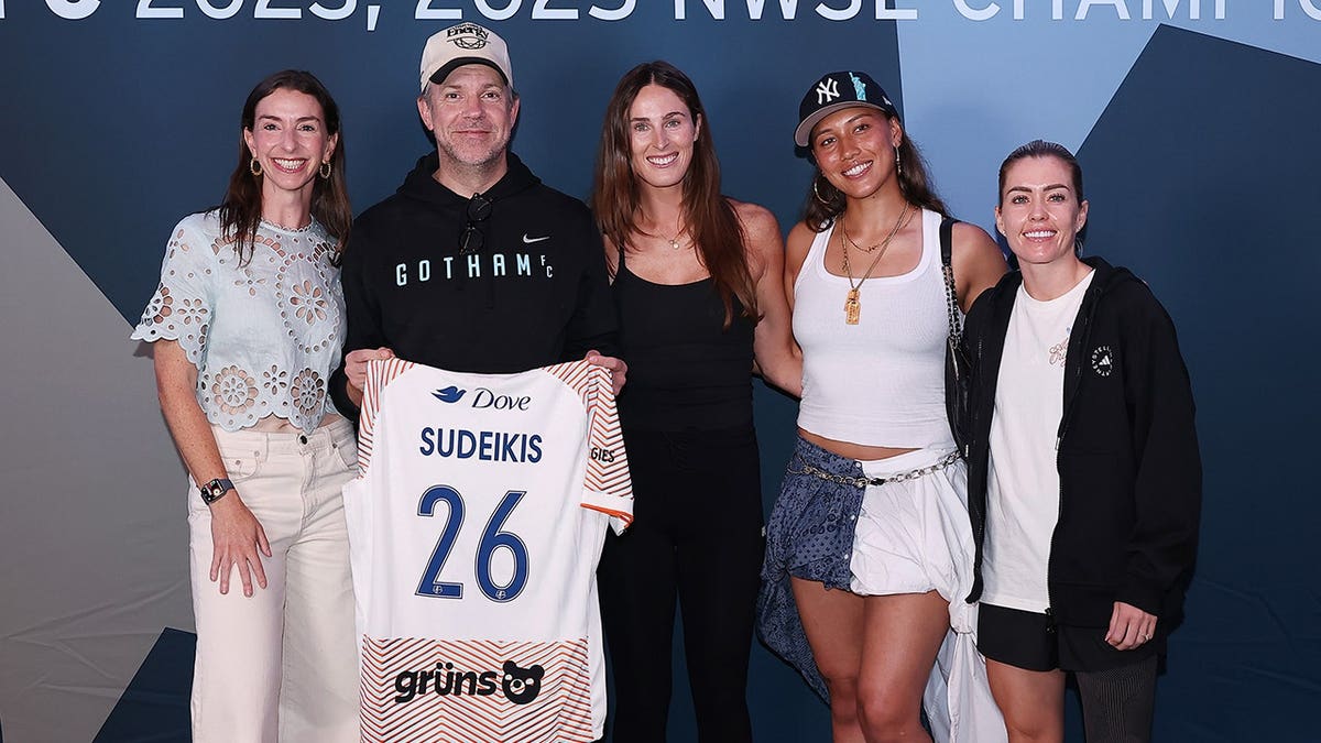 Jason Sudeikis poses with Gotham FC players and owner before an NWSL match.