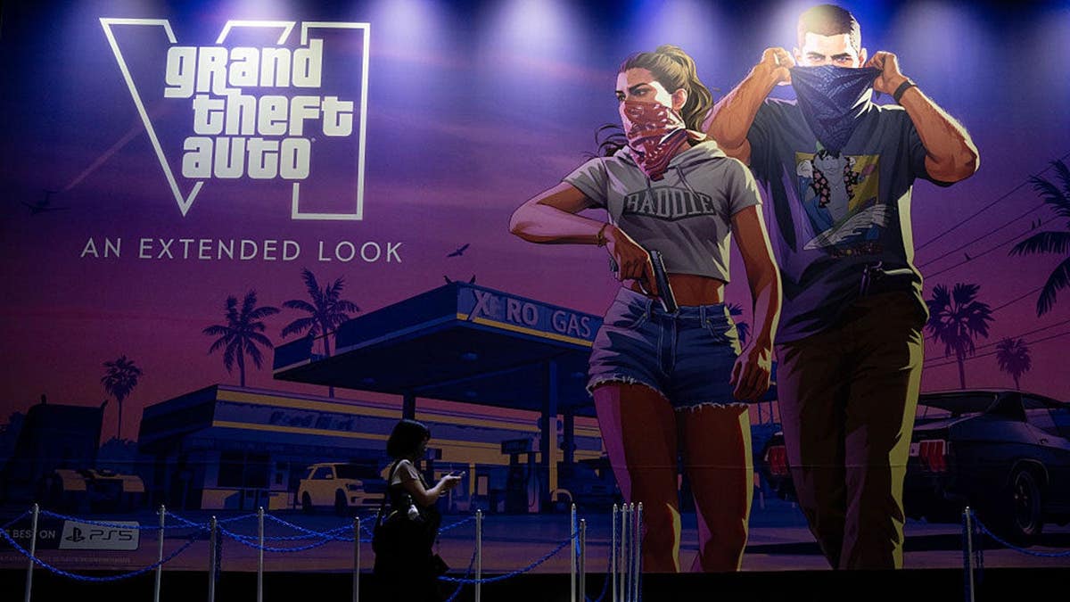 Attendees walk past a Grand Theft Auto VI promotional display at the Sony booth.