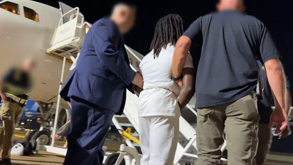 Haitian illegal immigrant Wisteguens Jean Quely Charles is escorted by federal agents to a plane. Charles was deported by ICE.