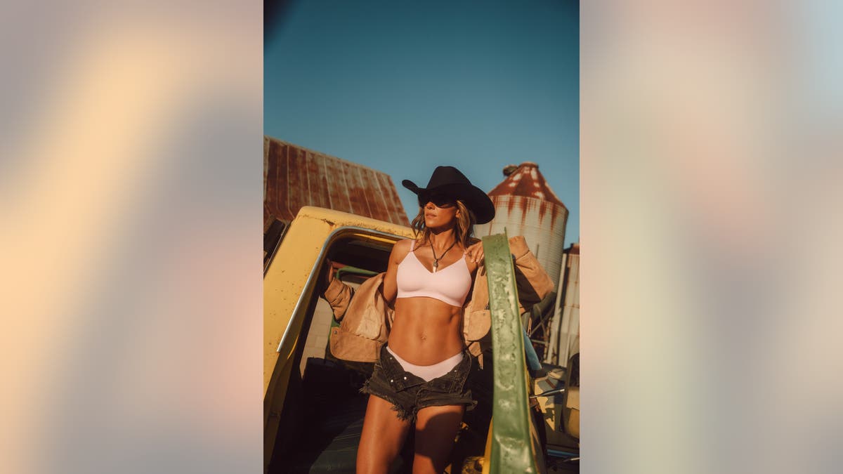Jana Kramer in a pink bra and underwear set sitting on truck
