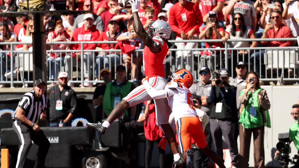 Jeremiah Smith #4 catches a touchdown pass while defended by Juice Clarke #6 during a football game.