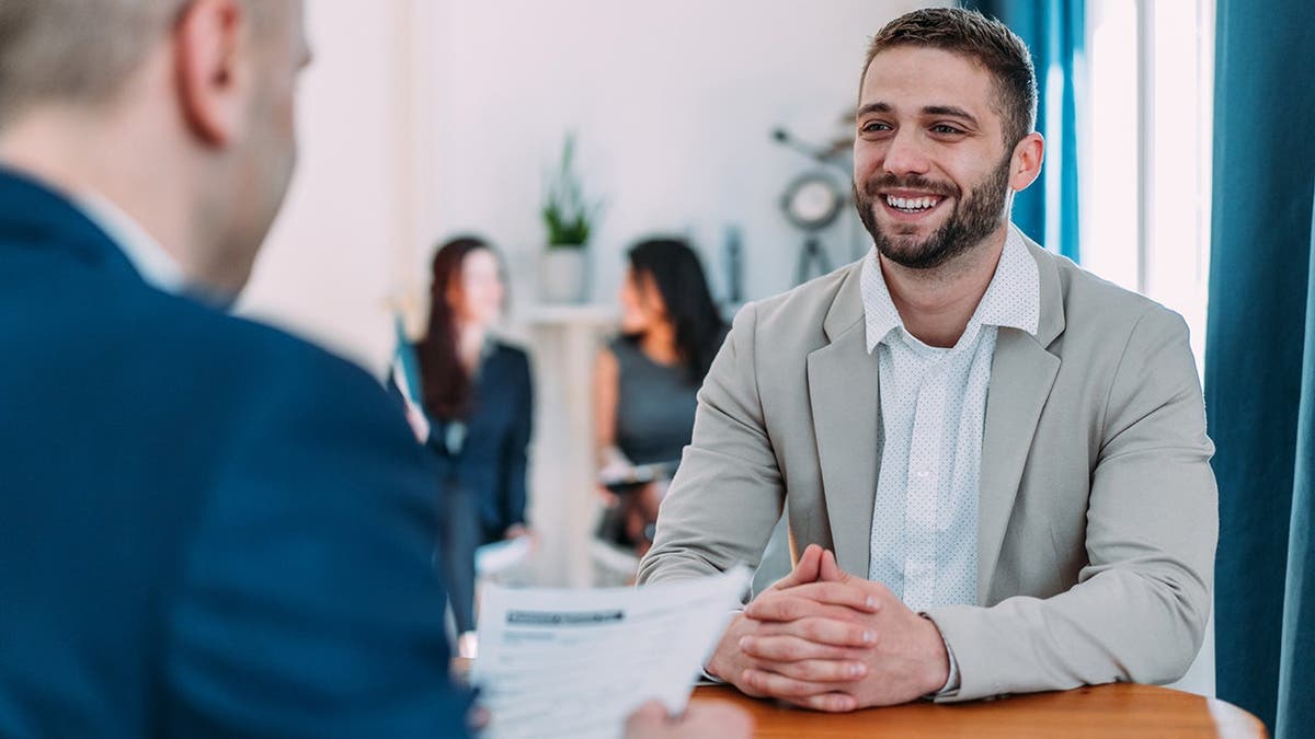Male HR manager reviews resume with young man during job interview.