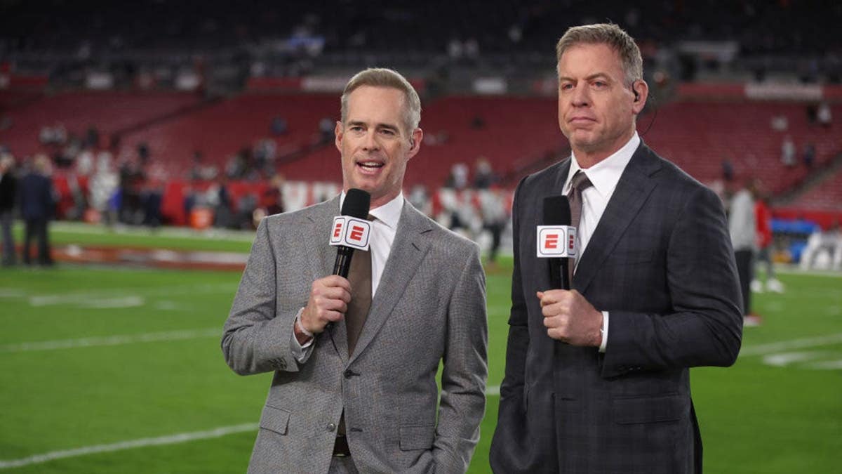 Joe Buck and Troy Aikman stand on the sideline before an NFL wild-card playoff game.