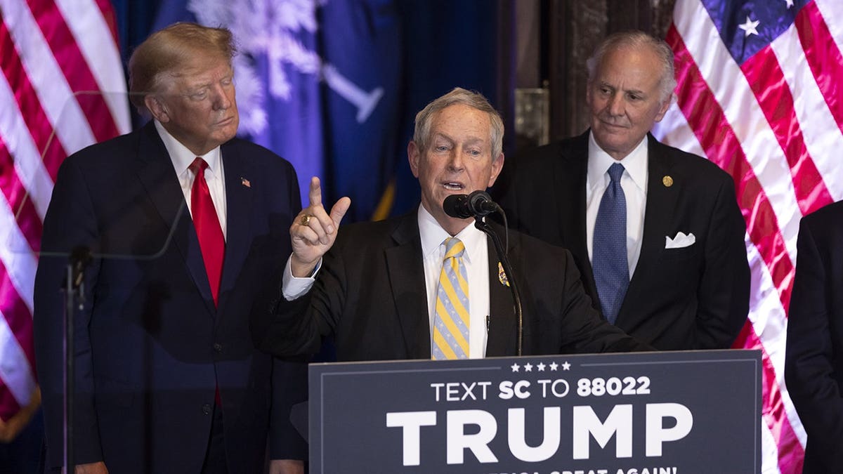 Rep. Joe Wilson speaks as former President Donald Trump and Gov. Henry McMaster listen during a campaign event.