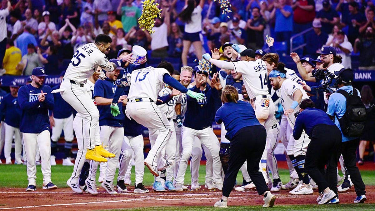 Junior Caminero celebrates with teammates after hitting a walk-off home run at Tropicana Field.