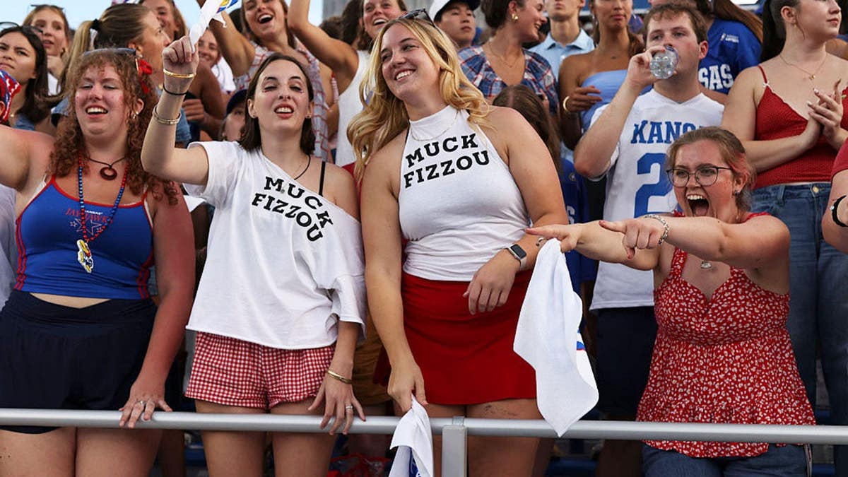 Kansas Jayhawks students wear shirts that say Muck Fizzou before a college football game.