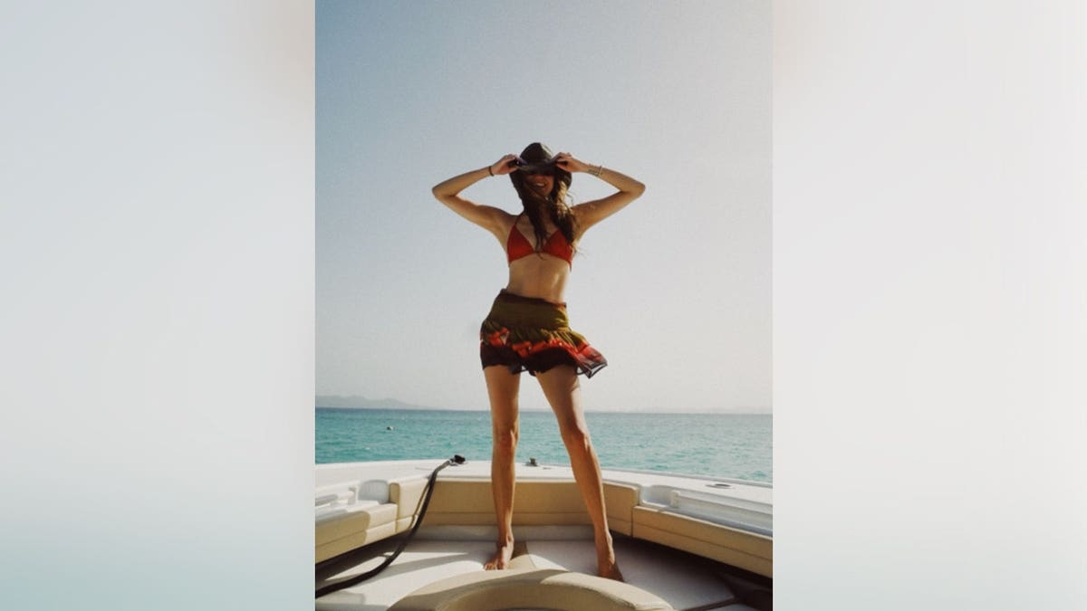 Kelsea Ballerini in a red bikini top and cowboy hat on a boat.