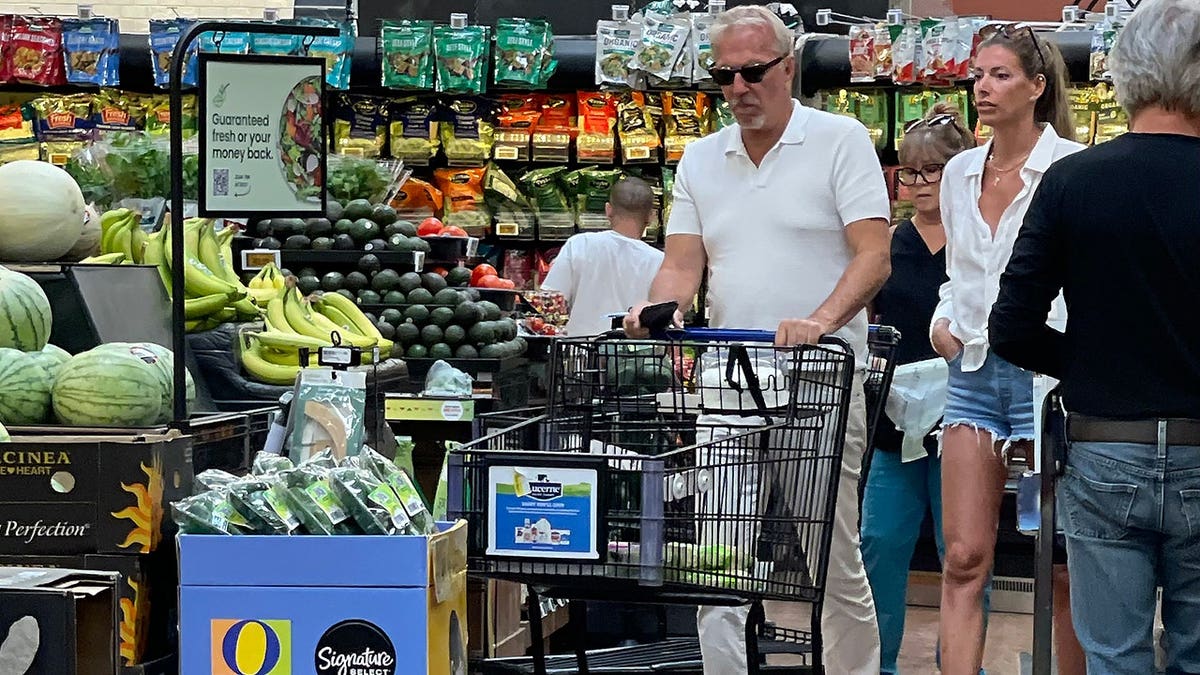 Kevin Costner and the lifestyle coach walking through the aisles of a grocery store.