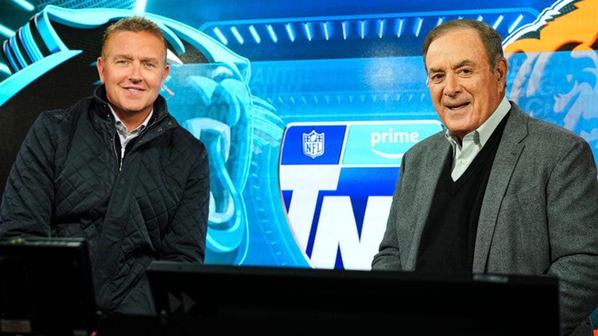 Kirk Herbstreit and Al Michaels stand in the Amazon Prime broadcast booth.