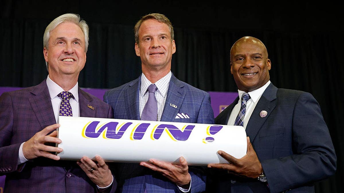 Lane Kiffin poses with LSU President Dr. Wade Rousse and interim athletic director Verge Ausberry at a press conference.