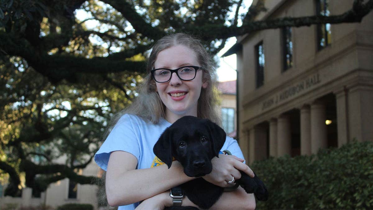 LSU Canine Companions club president Kelsey Johnson is seen with a future service dog in training on the LSU campus.