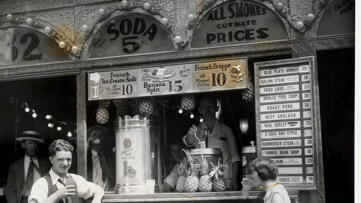 People hang out outside of a luncheonette in New York City in the early 20th century.