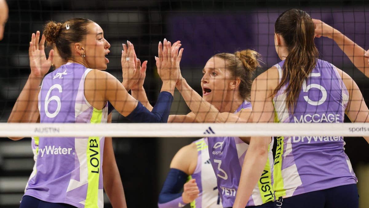 Madisen Skinner y Carli Lloyd se dan un choque de manos tras marcar un punto en un partido de voleibol.