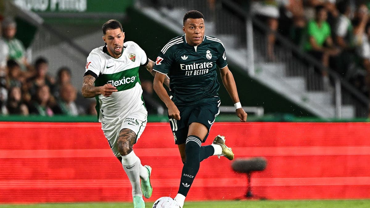 Kylian Mbappe runs with the ball under pressure from Tete Morente during a match.