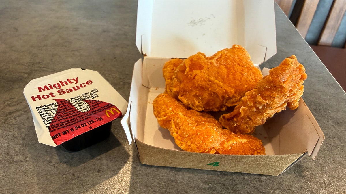 McDonald's Chicken McNuggets next to a Mighty Hot Sauce packet.