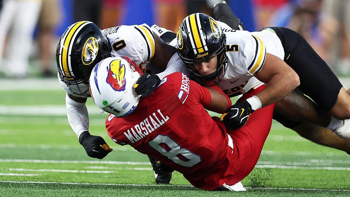 Robert Woodyard Jr. and Nicholas Rodriguez of Missouri tackle Isaiah Marshall of Kansas during a college football game.