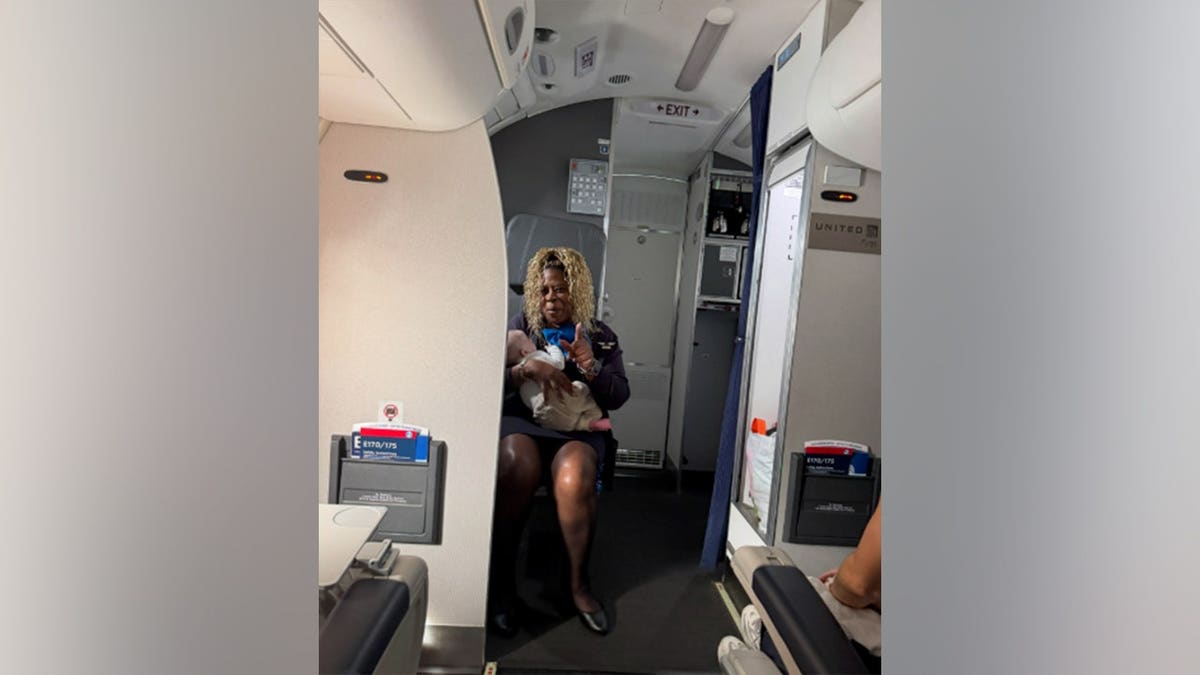 flight attendant Monique Harris smiles as she holds the baby during the flight