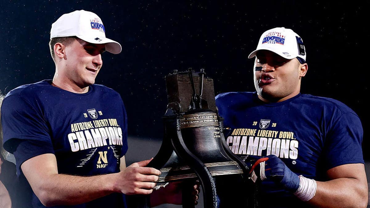 Blake Horvath and Landon Robinson hold the trophy after Navy wins the Liberty Bowl.